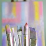 Art brushes with abstract painted canvas in vibrant colors.