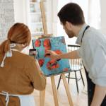 Art teacher instructs student in a creative painting lesson indoors, enhancing skills.