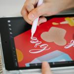 Close-up of hand drawing digital art with a stylus on a tablet, showcasing modern creativity.